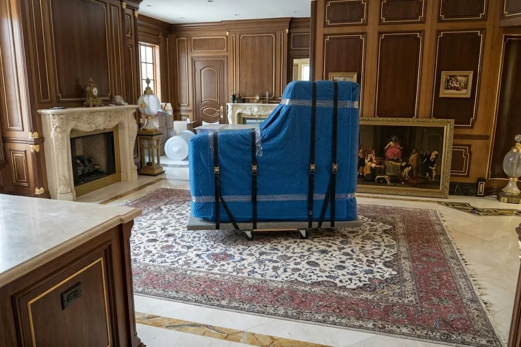 Grand piano wrapped in blue quilted blankets for transport